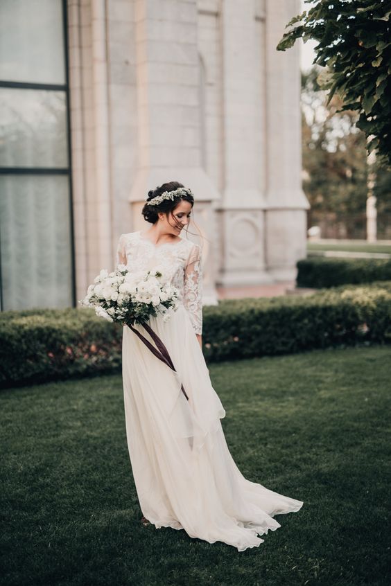 a modest wedding dress with a lace bodice with three quarter sleeves and a layered flowy skirt