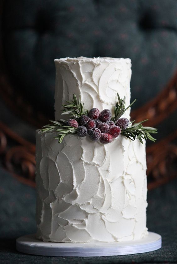 a white textural buttercream wedding cake with evergreens and sugared berries for a clean yet catchy look
