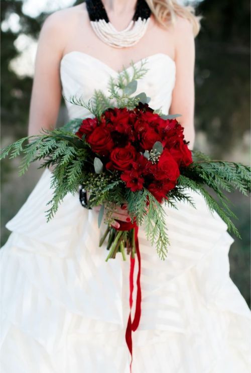 a Christmas wedding bouquet of evergreens, eucalyptus and red roses plus red ribbons