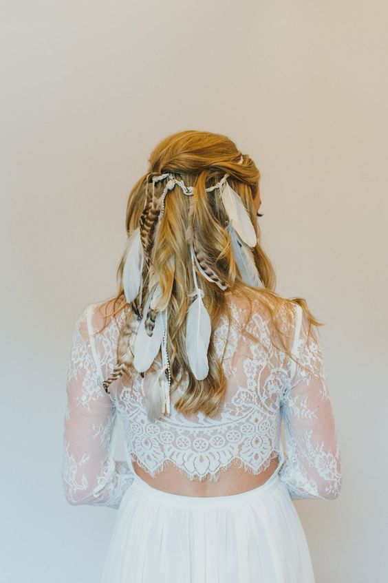 a half updo with a bump and waves spruced up with a lot of feathers is inspired by vikings and is ideal for a boho bride