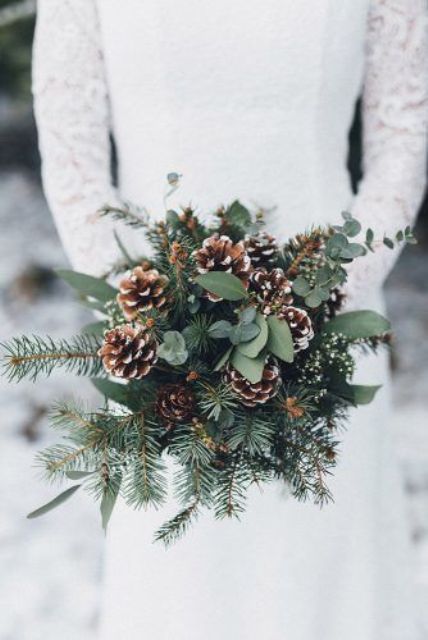 a cozy rustic winter wedding bouquet with evergreens, eucalyptus and snowy pinecones