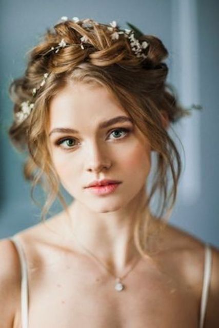 a large braided crown updo with locks down and fresh blooms tucked in is a chic and fresh hairstyle for a boho bride