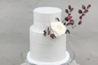 19 a purely white wedding cake decorated with dark foliage and a single white blooms for an early fall wedding with a Nordic twist