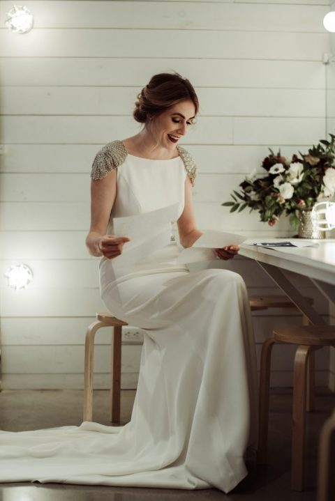 a plain sheath wedding dress with embellished cap sleeves, a train and an open back