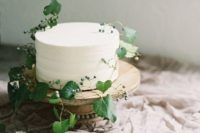 21 a simple and natural white wedding cake decorated with fresh greenery and berries for a delicate Nordic spring wedding