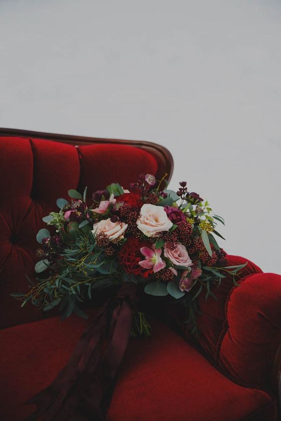 a luxurious rich wedding bouquet of blush and deep red blooms, lots of greenery and berries
