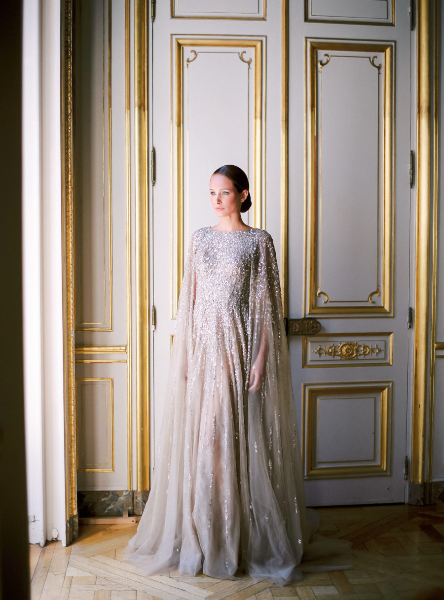 A silver grey wedding dress with heavy embellishments and a matching cape for a fashion forward bride