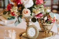 22 a vintage-inspired centerpiece of a gold tray, a picture frame, a duo of vases with blooms for a stunning vintage wedding