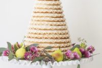 23 a kransekake topped with blooms and greenery and displayed on a stand with fruits, blooms and greenery
