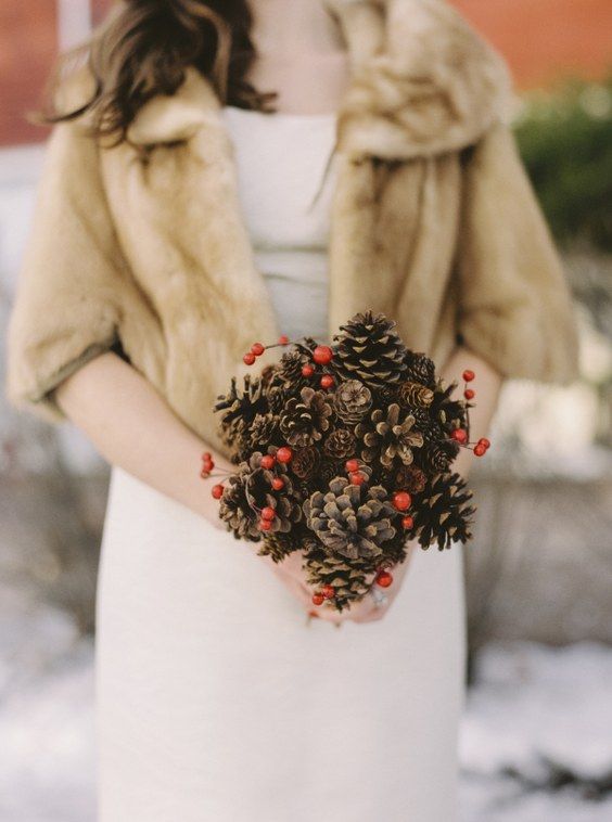 a simple Christmas wedding bouquet of pinecones and holly berries is a budget-friendly idea