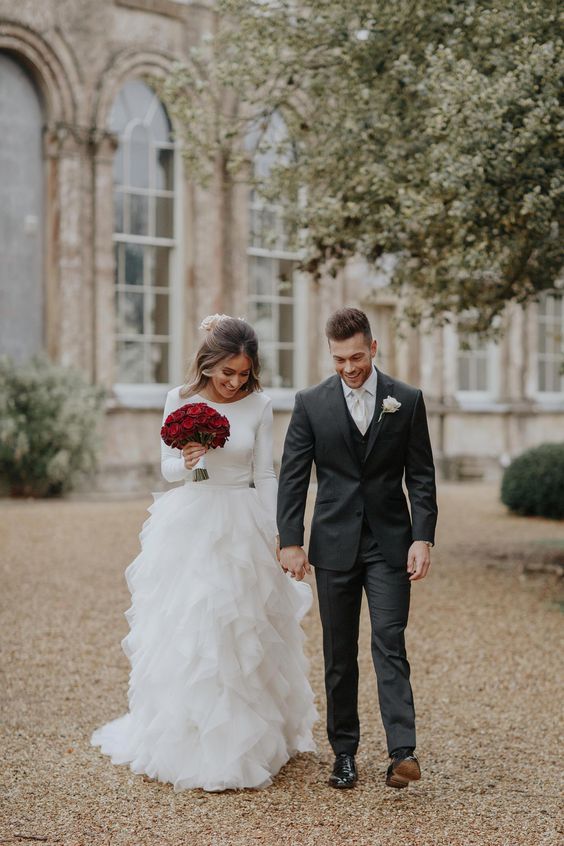 a unique wedding gown with a plain bodice wit long sleeves and a ruffled skirt, which is a fresh take on romantic ruffled dresses