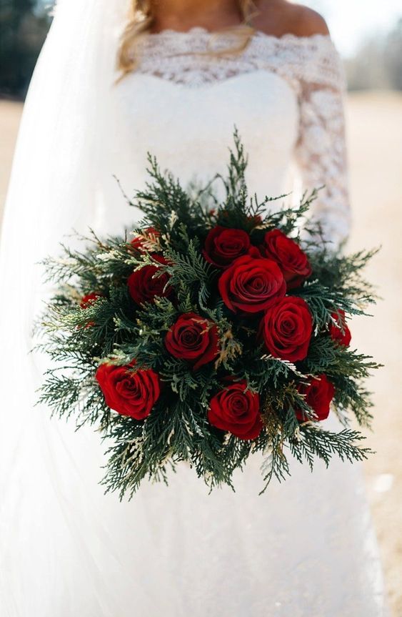 a simple holiday wedding bouquet of evergreens and red roses is a chic idea
