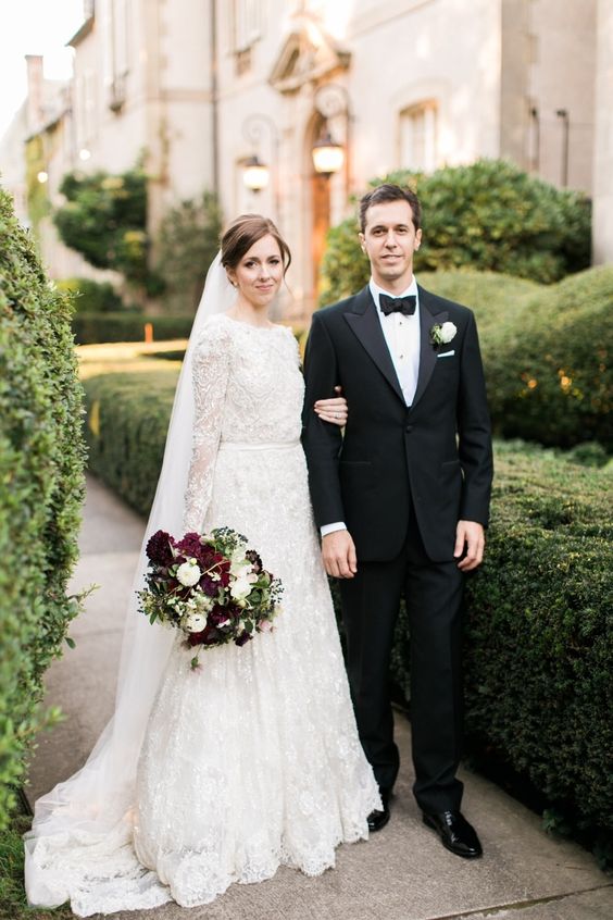 a vintage-inspired lace A-line wedding dress with long sleeves, a high neckline and a matching veil