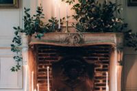 26 a refined fireplace with lush greenery and candles all around will become a perfect wedding backdrop