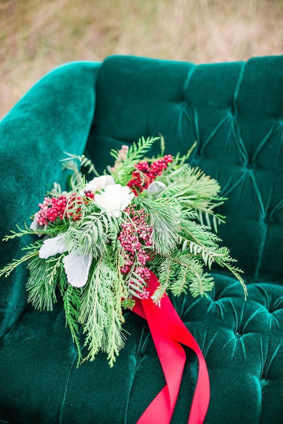 a textural wedding bouquet of evergreens, white blooms and berries plus red ribbons