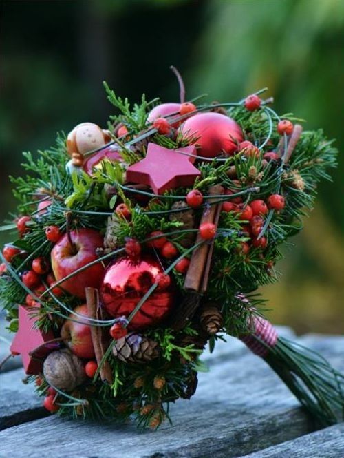 A unique Christmas wedding bouquet of evergreens, red apples, ornaments, nuts and holly berries