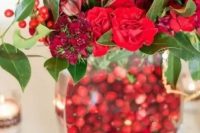 a bold winter centerpiece of a vase filled with cranberries, red blooms, leaves and berries is a perfect winter or Christmas wedding decoration you may easily make
