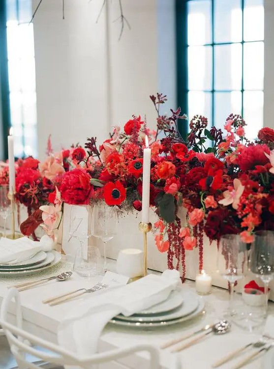 a lush and bold red winter wedding centerpiece with peonies, anemones, roses and tulips plus dark foliage is wow