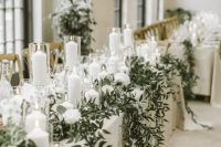 a luxurious winter wedding tablescape with white linens, white blooms, candles, greenery hanging down is a refined and beautiful idea to go for