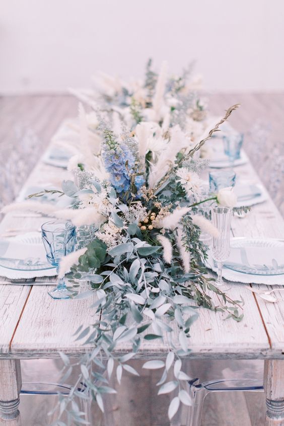 a neutral winter wedding centerpiece of blue blooms, dried herbs, greenery and berries is a cool idea for a frozen wedding