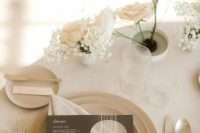 a neutral winter wedding place setting with white and blush roses and baby’s breath, neutral plates and simple modern cutlery