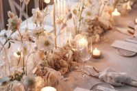 a neutral winter wedding table runner with dried leaves, blooms and super thin and tall candles is a gorgeous idea