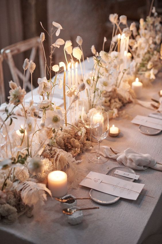 a neutral winter wedding table runner with dried leaves, blooms and super thin and tall candles is a gorgeous idea