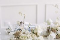 a white winter wedding centerpiece of roses, ranunculus and other blooms is a stylish idea for a neutral winter wedding