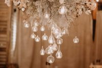 an overhead floral installation with baby’s breath, cotton branches and some bubbles with candles is amazing