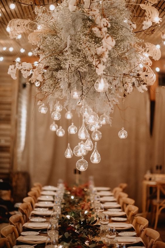an overhead floral installation with baby's breath, cotton branches and some bubbles with candles is amazing