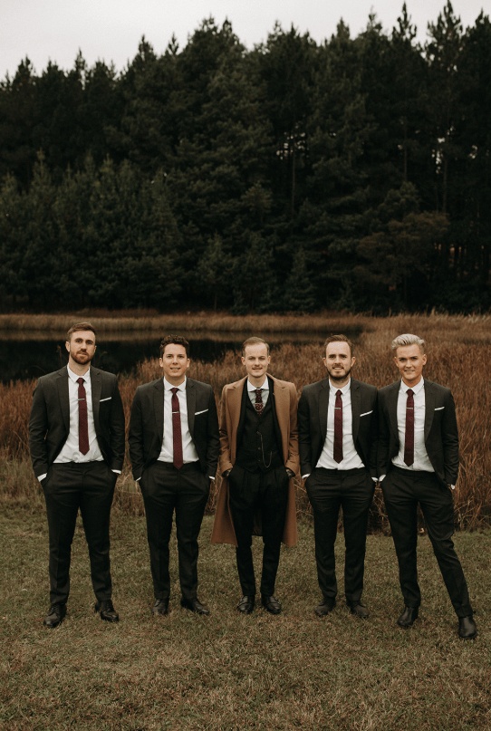 The groom was rocking a grey three-piece suit, a burgundy tie and a camel coat, the groomsmen were wearing two piece grey suits with burgundy ties