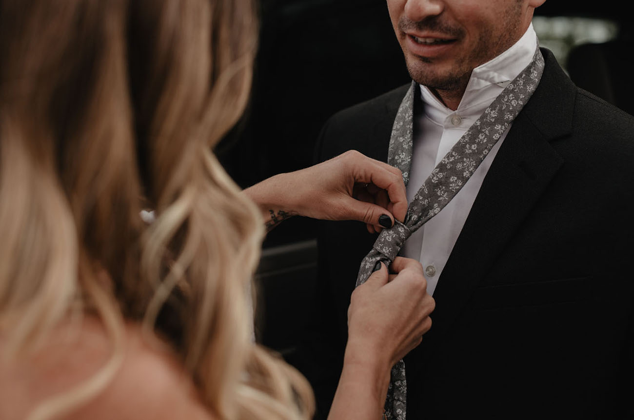 The groom was wearing a black suit with a floral print tie in grey