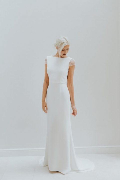 a simple fitting wedding dress with cap sleeves embellished with pearls and a high neckline
