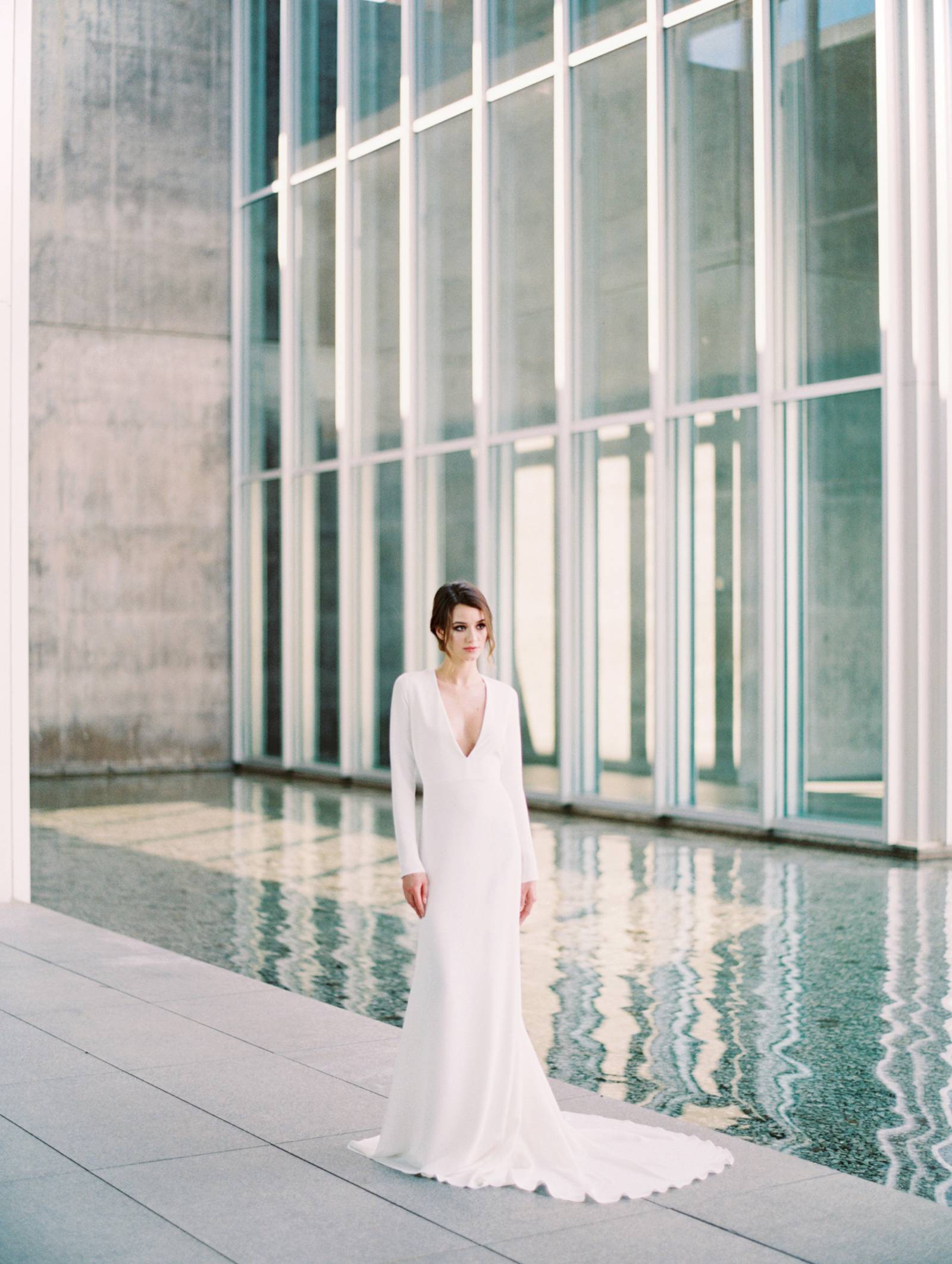 A minimalist wedding gown with a plunging neckline, long sleeves, a train for a Nordic bride