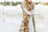 10 a luxurious long fur coat without sleeves but with a train is a statement piece in this bridal outfit