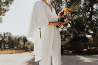 13 a fantastic minimalist white jumpsuit with a deep V-neckline, cape sleeves and statement earrings