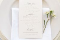 14 a minimalist spring-inspired place setting with matte plates, a white napkin and a neutral card plus blooms