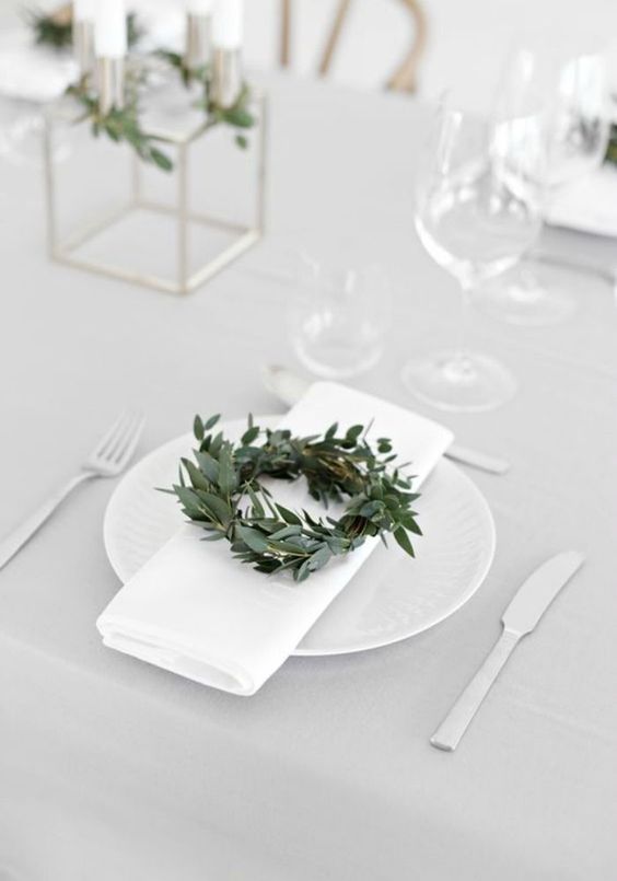 a modern winter wedding tablescape with a little greenery wreath, all white everything and some candles