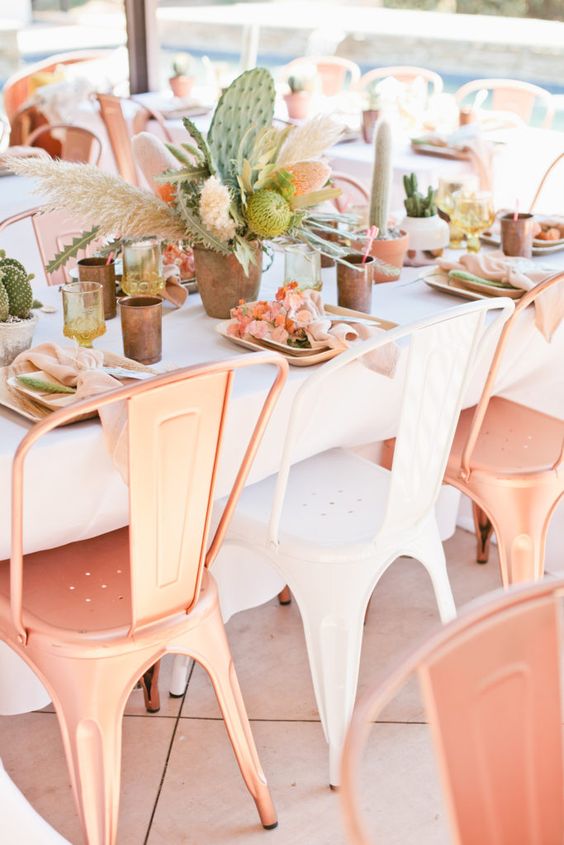 copper chairs, copper chargers, peachy napkins and blooms and a lush greenery, cactus and pampas grass centerpiece