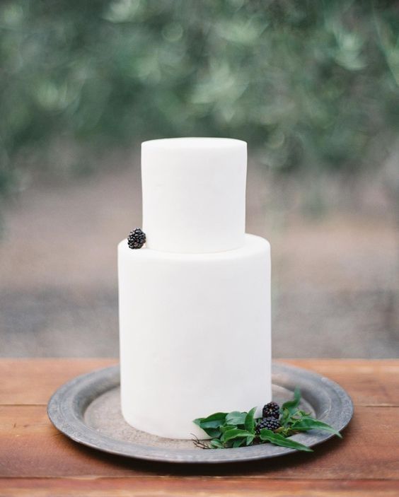 a minimalist plain white wedding cake topped with a single blackberry is a gorgeous idea for a minimalist wedding