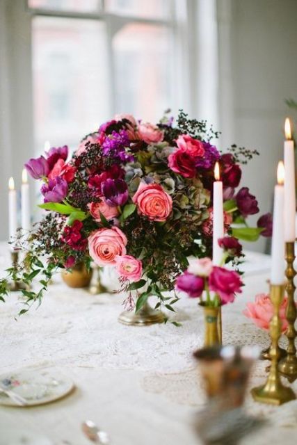 a lush wedding centerpiece in coral, purple, hot pink, textural greenery and berries is great for a decadent wedding