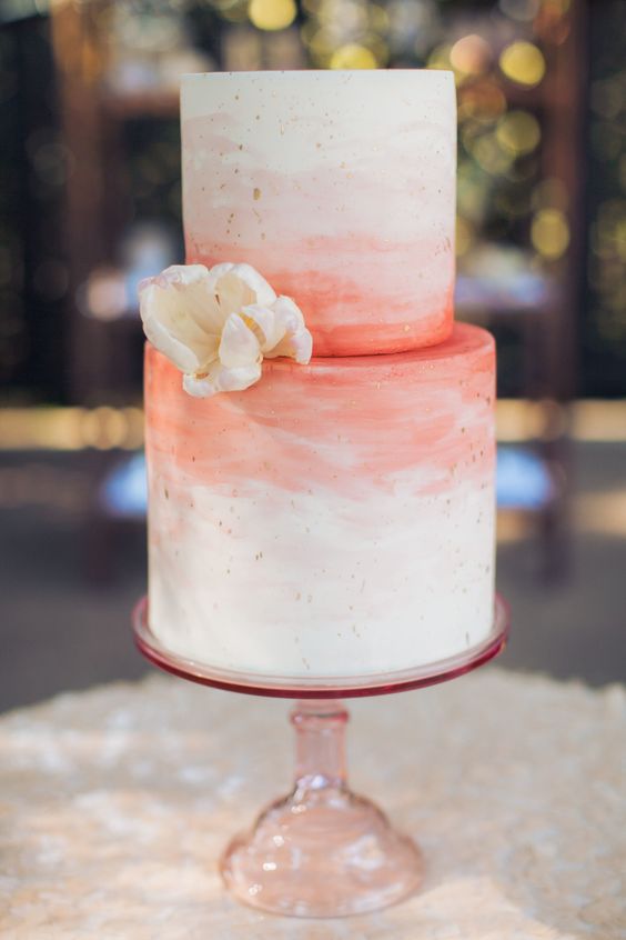 a watercolor brushstroke wedding cake in white and coral with gold leaf dots and a sugar flowers