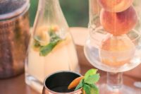 24 a stylish wedding bar with copper mugs, trays and jars and real peaches in a tall glass vase to add them to drinks