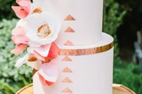 25 a white wedding cake decorated with copper leaf, with white and coral blooms on a wooden stand