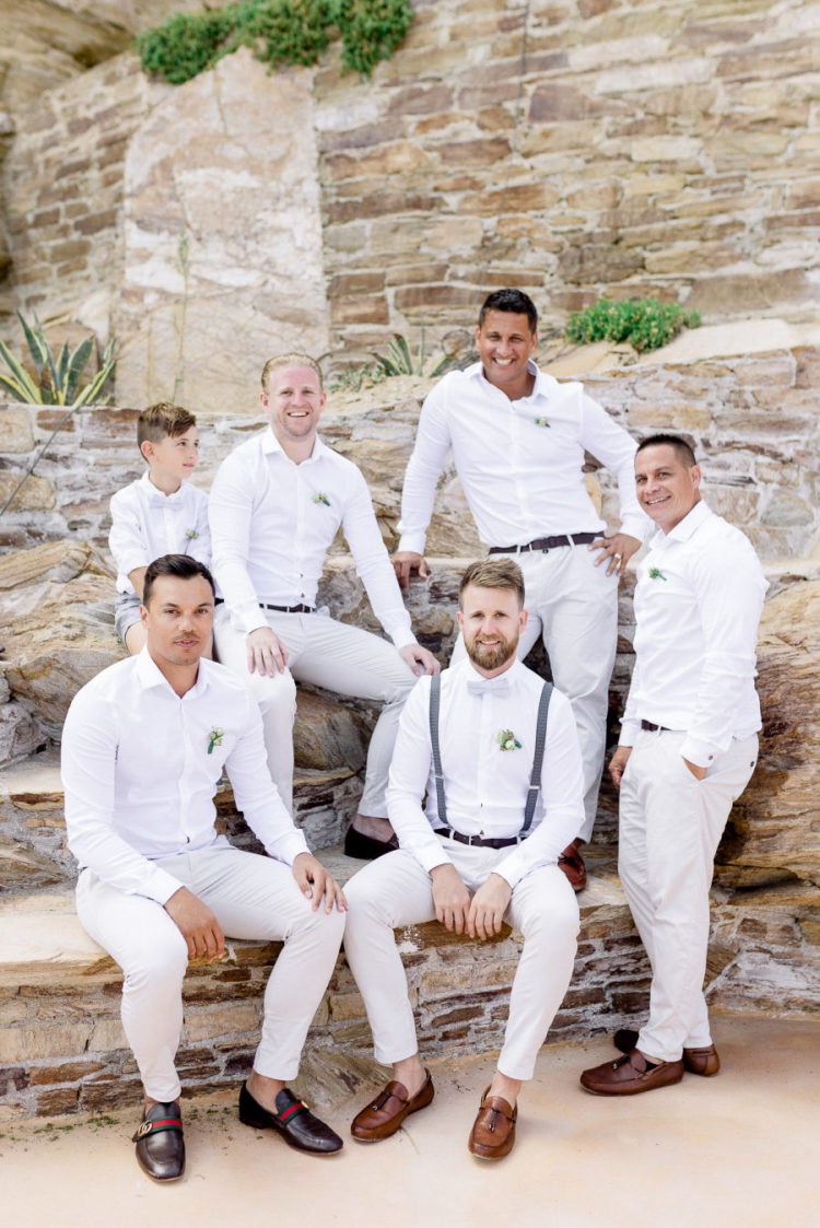The groom was wearing a white shirt and pants, brown moccasins and blue suspenders, and the groomsmen were wearing the same