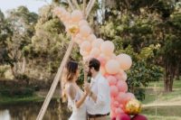 05 a fresh and modern take on a boho wedding arch with peachy, gold and plum-colored balloons