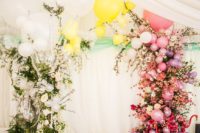 06 a dazzling wedding arch made with greenery, white and sheer balloons on one side and colorful blooms and balloons on the other