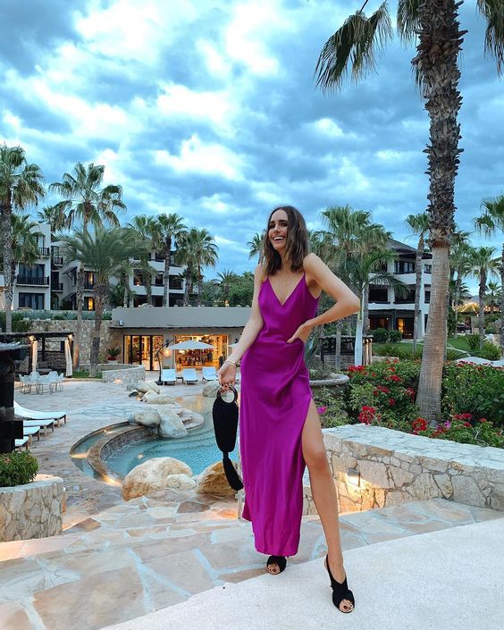 a hot purple silk maxi dress with a side slit, black criss cross shoes and a black bag with a tassel