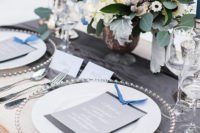07 Metallic chargers, silver cutlery, blue candles and grey menus create a chic winter tablescape