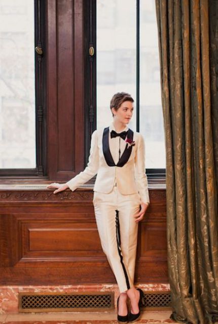 an elegant creamy tuxedo with black lapels, a white shirt and a black bow tie plus black heels is a stylish statement
